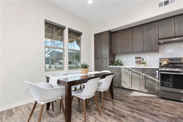 kitchen with dark hardwood / wood-style flooring, decorative backsplash, gas range, and dark brown cabinetry