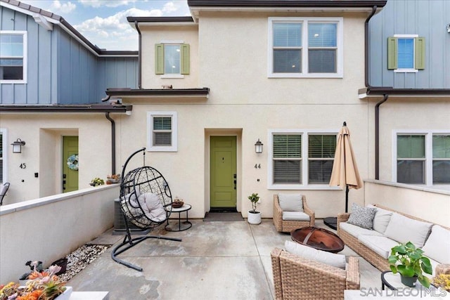 rear view of house featuring a patio and an outdoor living space with a fire pit