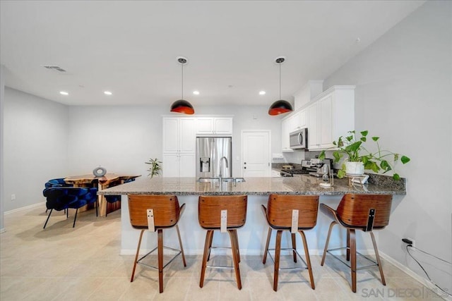 kitchen with sink, appliances with stainless steel finishes, white cabinetry, light stone countertops, and kitchen peninsula