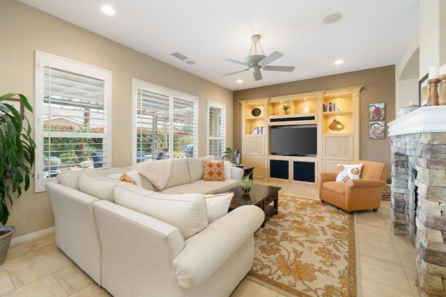 living room with a stone fireplace, light tile patterned floors, and ceiling fan