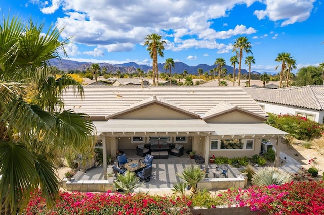 back of property featuring a mountain view, a patio area, and outdoor lounge area