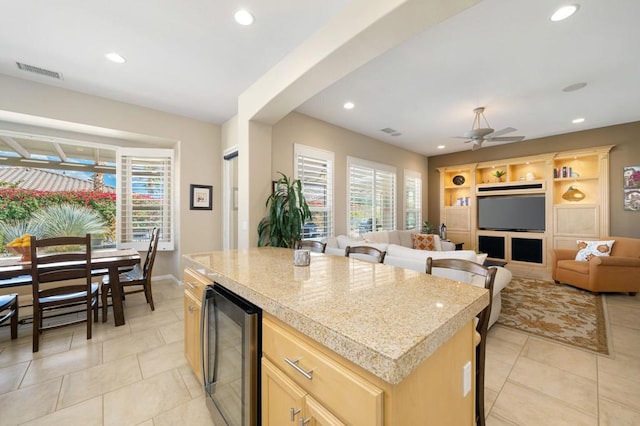 kitchen featuring light tile patterned flooring, light brown cabinetry, wine cooler, a center island, and ceiling fan