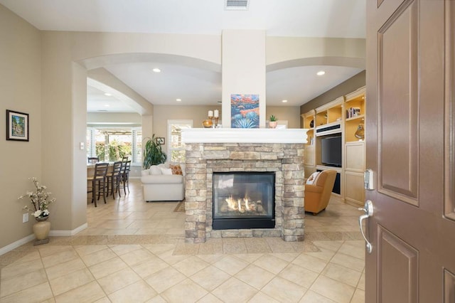 tiled living room with a stone fireplace