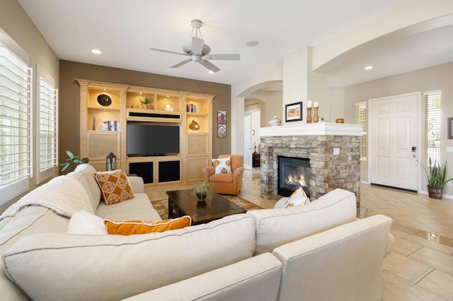 tiled living room with a fireplace and ceiling fan