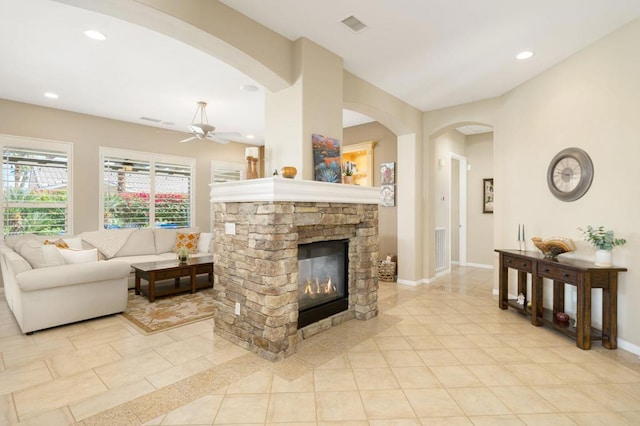 living room featuring ceiling fan, a fireplace, and light tile patterned floors