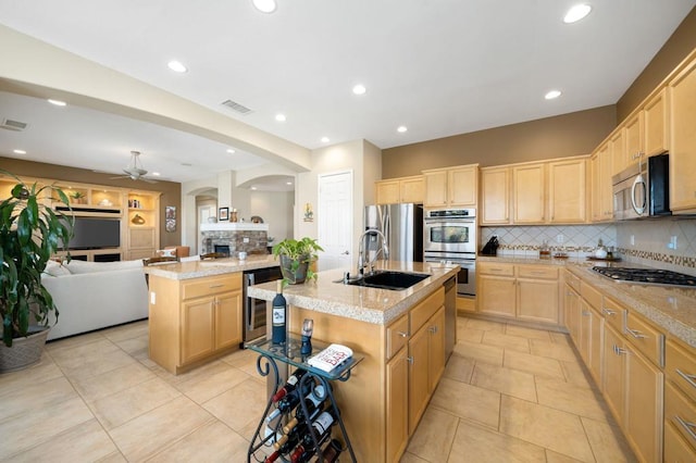 kitchen with wine cooler, stainless steel appliances, sink, and a center island with sink