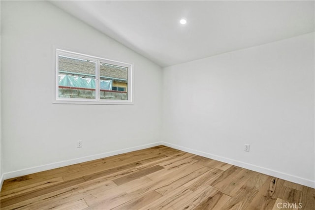 unfurnished room featuring lofted ceiling and light hardwood / wood-style floors