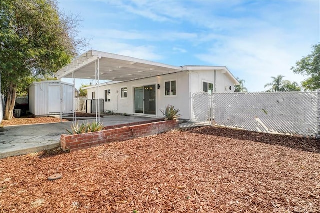 rear view of property with a storage shed and a patio