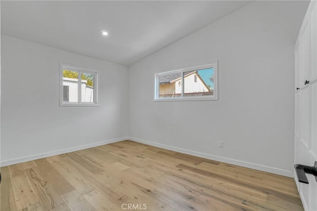 empty room with lofted ceiling and light hardwood / wood-style floors