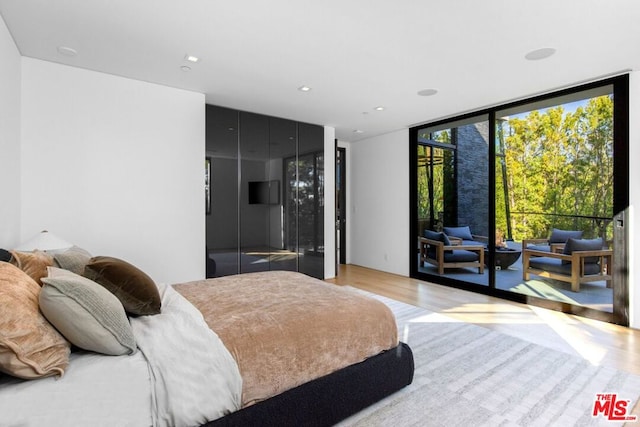 bedroom with access to exterior, expansive windows, and light wood-type flooring