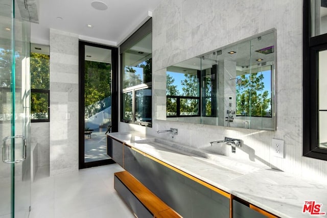 bathroom with decorative backsplash, vanity, a shower with shower door, and tile walls