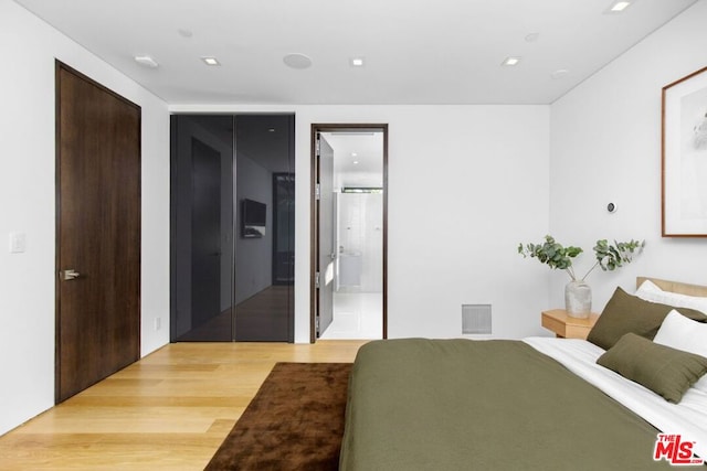 bedroom featuring wood-type flooring and ensuite bathroom