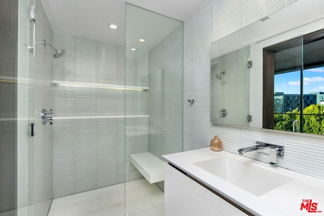 bathroom with backsplash, vanity, tile walls, and a tile shower