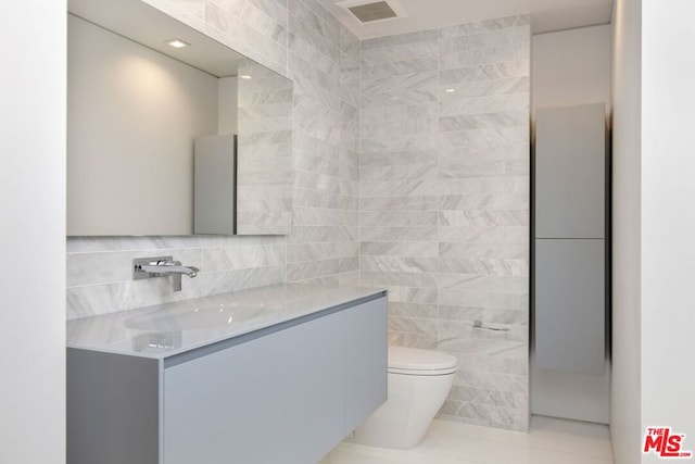 bathroom featuring vanity, toilet, tile patterned flooring, and tile walls