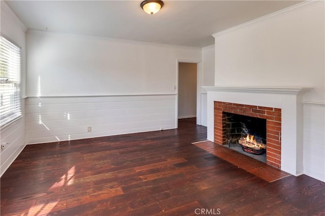 unfurnished living room featuring ornamental molding, a brick fireplace, and dark hardwood / wood-style floors