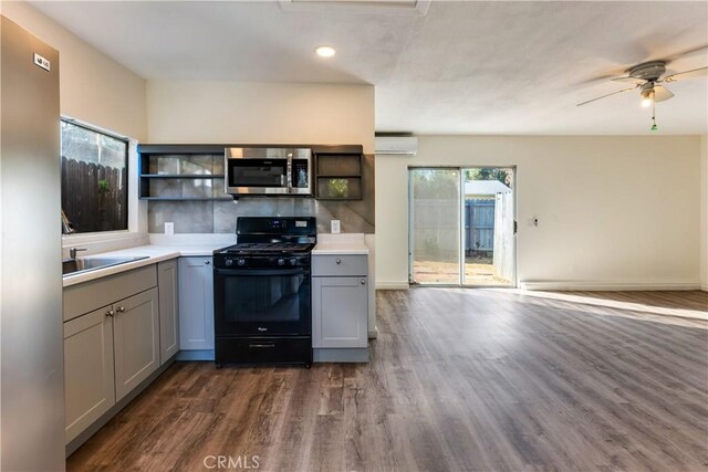 kitchen with gray cabinets, appliances with stainless steel finishes, an AC wall unit, and dark hardwood / wood-style flooring