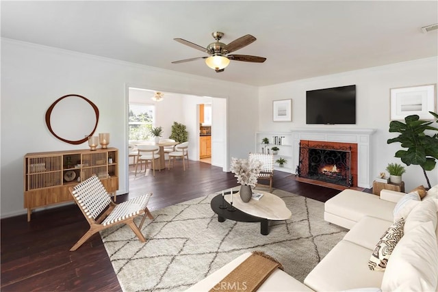 living room featuring a premium fireplace, crown molding, dark hardwood / wood-style floors, and ceiling fan