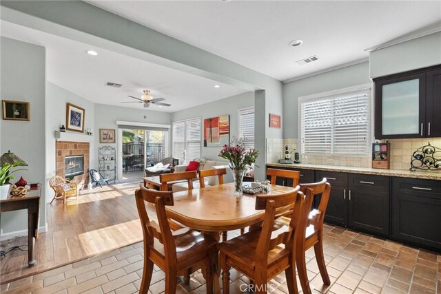 dining room with ceiling fan and a fireplace