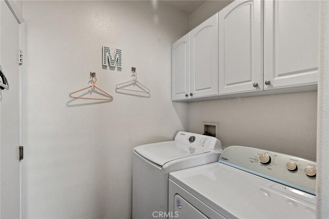 laundry room featuring washer and clothes dryer and cabinets