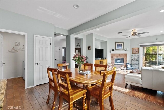 dining space with a brick fireplace and ceiling fan