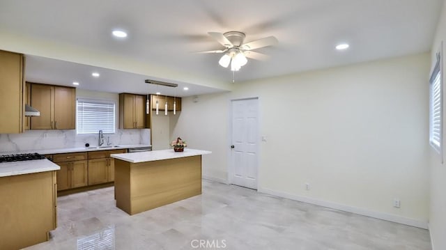 kitchen with sink, ceiling fan, a center island, decorative backsplash, and decorative light fixtures