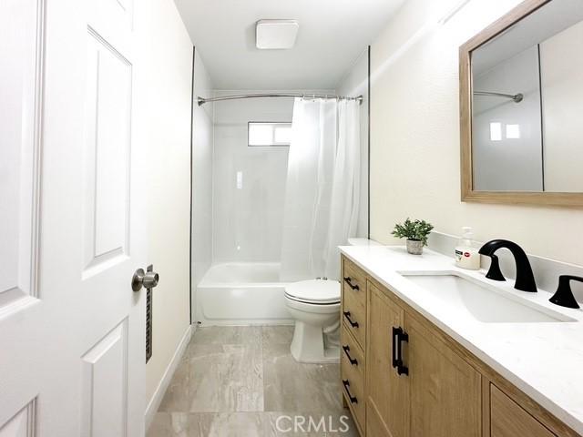 full bathroom with vanity, shower / tub combo, and toilet