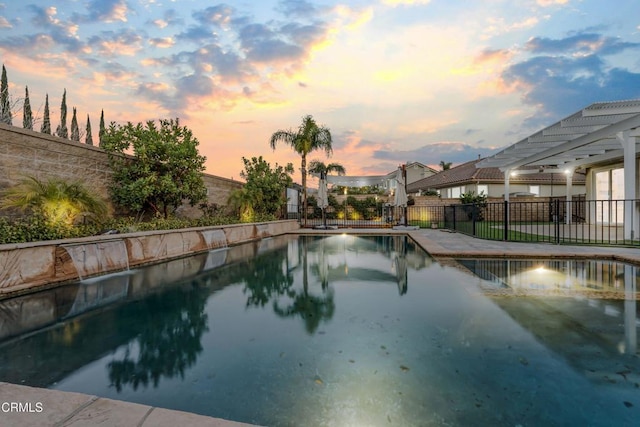 pool at dusk featuring a pergola