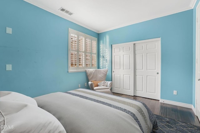 bedroom featuring dark wood-type flooring, ornamental molding, and a closet