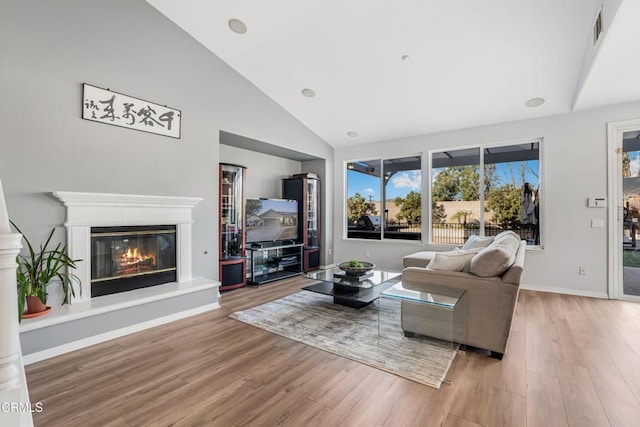 living room featuring high vaulted ceiling and light hardwood / wood-style flooring