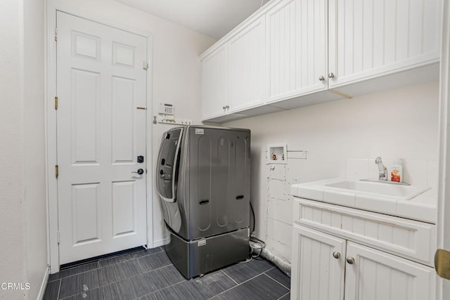 laundry room featuring cabinets, washer / clothes dryer, sink, and dark tile patterned floors