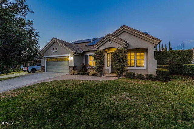 view of front of house with a garage, a yard, and solar panels