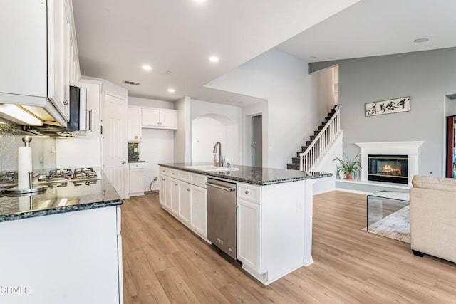 kitchen featuring white cabinetry, sink, stainless steel appliances, a center island with sink, and light hardwood / wood-style flooring