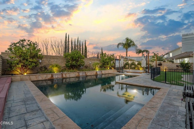 pool at dusk with a patio area