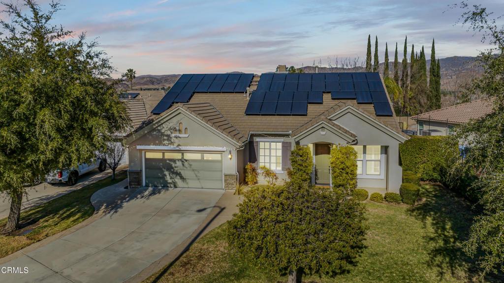 view of front of property featuring a garage, a yard, and solar panels