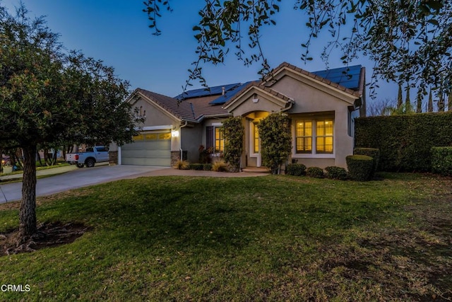 view of front of home with a garage, a yard, and solar panels