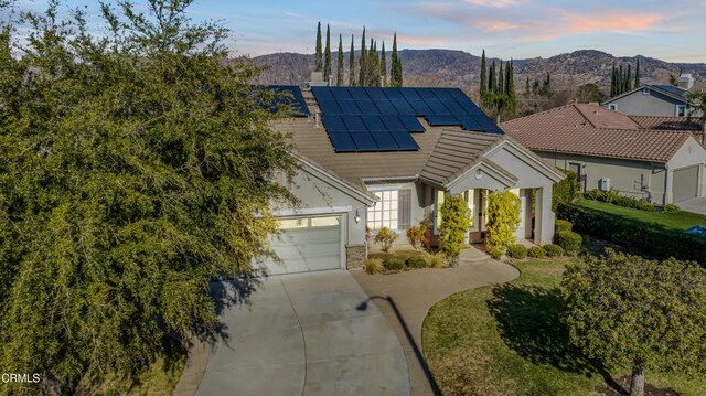 view of front facade with a mountain view, a garage, and solar panels