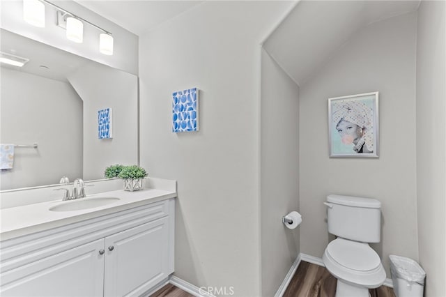 bathroom featuring vanity, wood-type flooring, lofted ceiling, and toilet