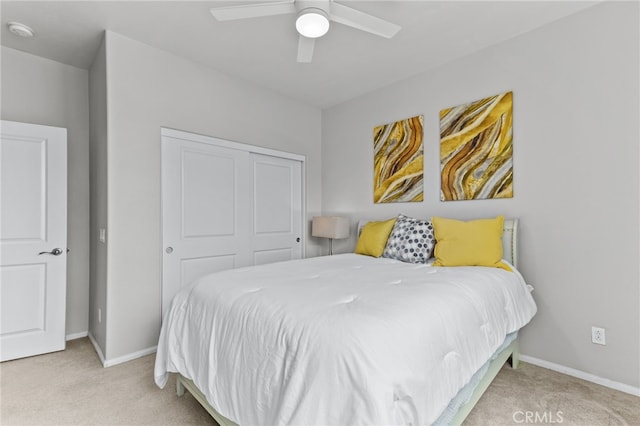 bedroom featuring light colored carpet, a closet, and ceiling fan