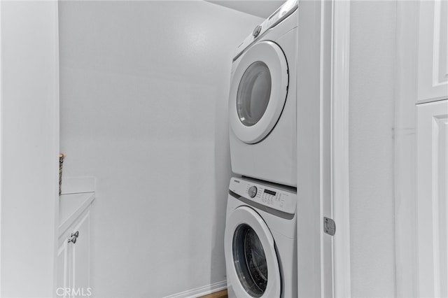 laundry room featuring cabinets and stacked washer / dryer