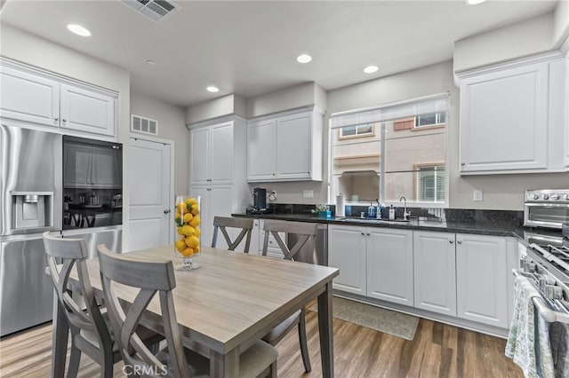 kitchen featuring hardwood / wood-style flooring, appliances with stainless steel finishes, sink, and white cabinets