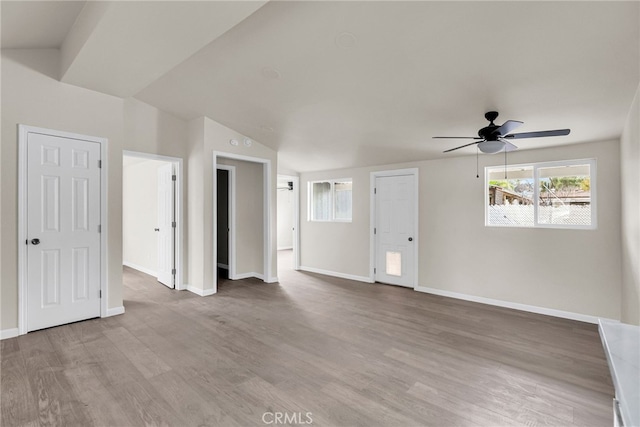 empty room with ceiling fan, lofted ceiling, and light wood-type flooring