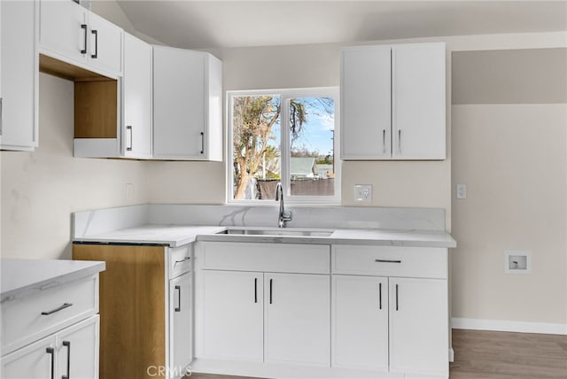 kitchen with sink, hardwood / wood-style floors, and white cabinets