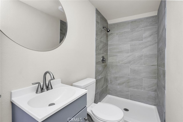 bathroom with vanity, toilet, and a tile shower