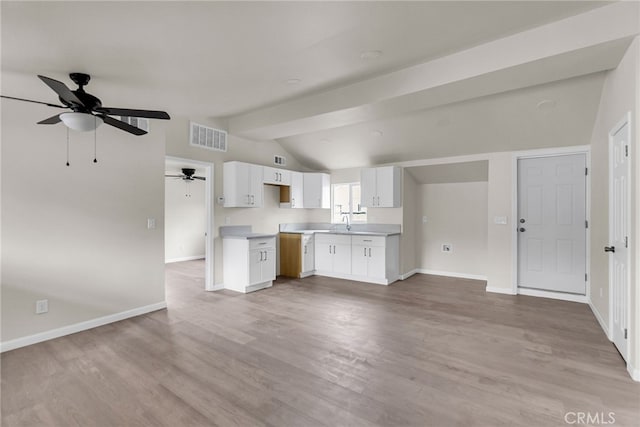 kitchen with sink, lofted ceiling with beams, light hardwood / wood-style flooring, ceiling fan, and white cabinets