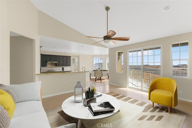 living room featuring lofted ceiling, sink, and ceiling fan with notable chandelier