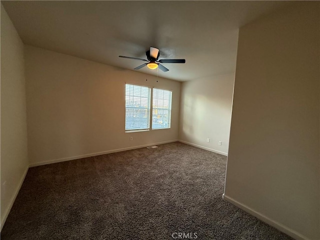 empty room featuring ceiling fan and dark carpet