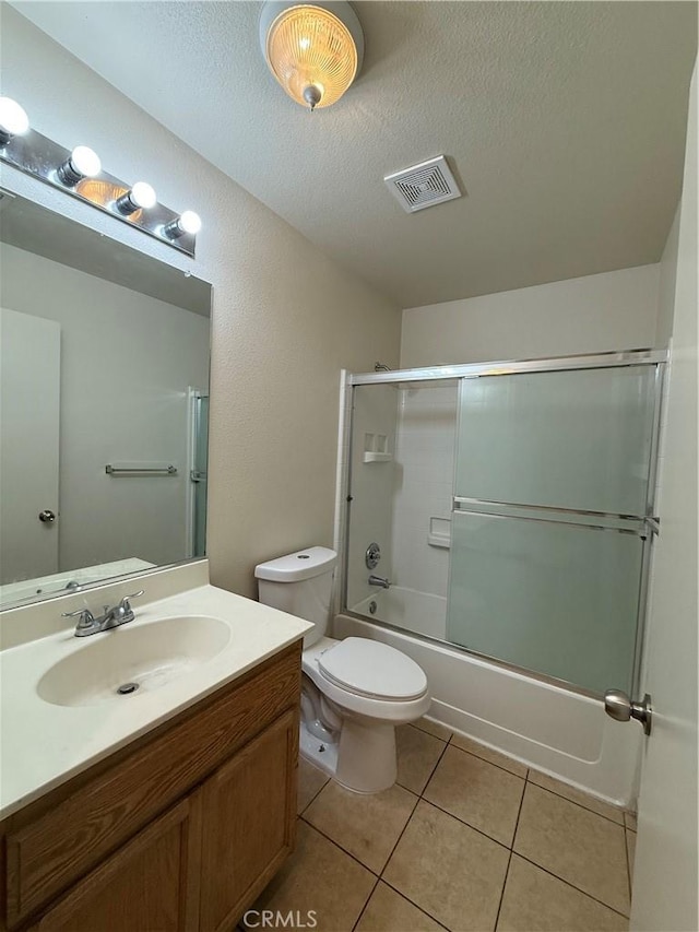 full bathroom with enclosed tub / shower combo, tile patterned flooring, vanity, a textured ceiling, and toilet