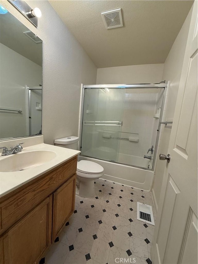 full bathroom featuring vanity, a textured ceiling, shower / bath combination with glass door, and toilet