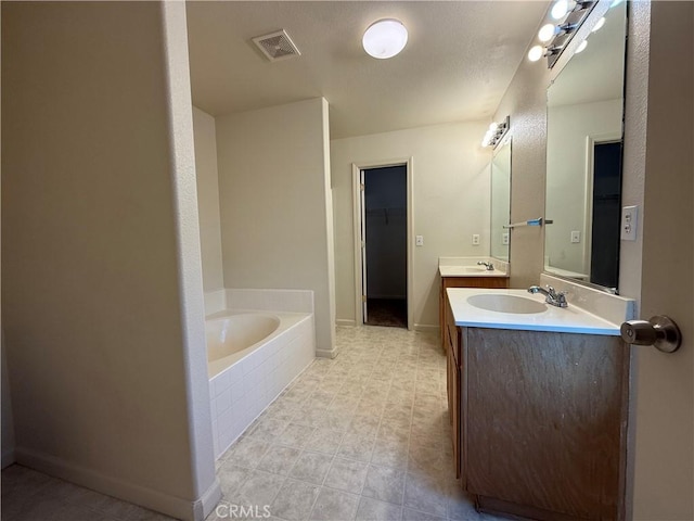 bathroom with a relaxing tiled tub and vanity