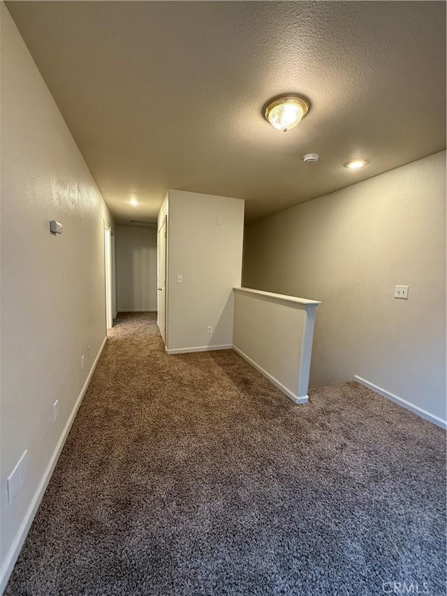 corridor featuring a textured ceiling and carpet flooring